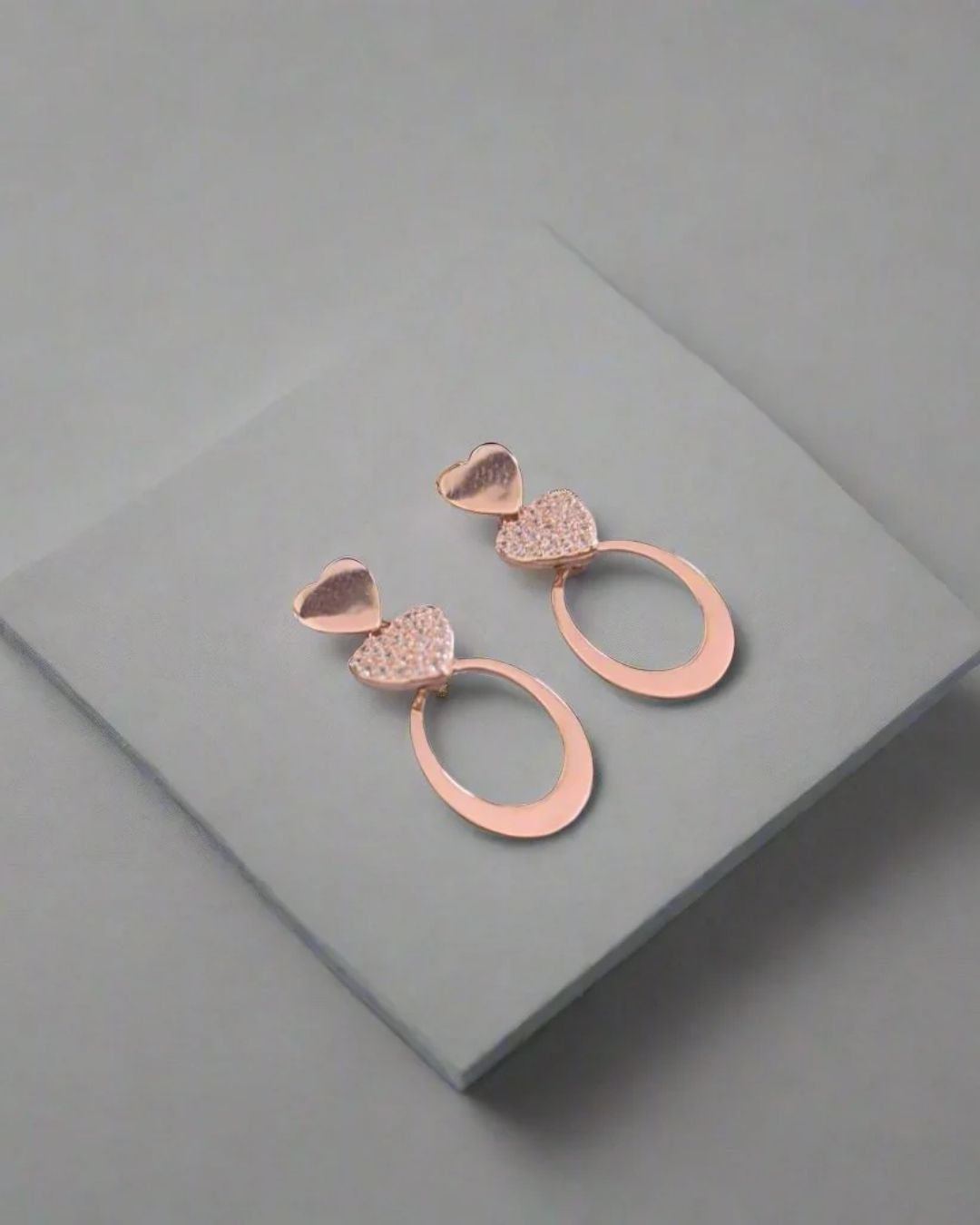 Rose gold earrings on a gray surface