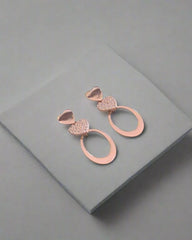 Rose gold earrings on a gray surface