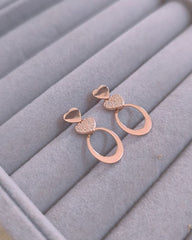 Rose gold earrings on a gray jewelry display