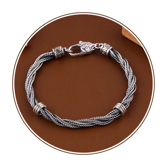 Silver braided bracelet on a brown circular background