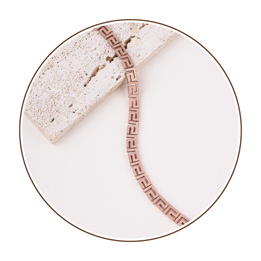 Rose gold bracelet on a white plate with a slice of cake