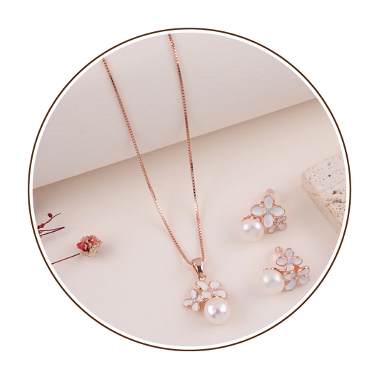 Rose gold necklace and earrings on a beige surface with a white background