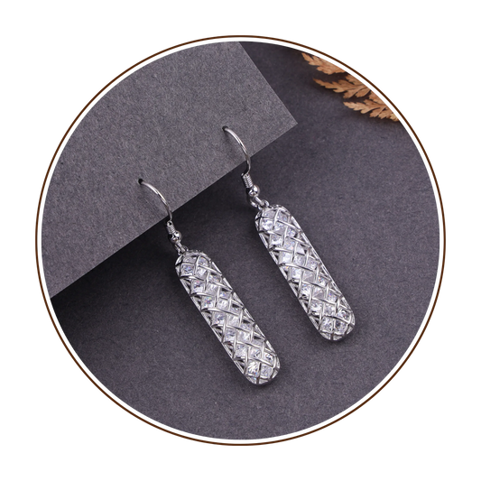 Pair of silver earrings on a gray surface with a blurred background